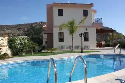 a villa with a swimming pool in front of a house at Holidays Villas in Pissouri