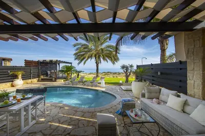 a patio with a pool with a couch and a table at Protaras El Greco Seafront Villa, Greco Mare in Protaras