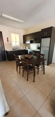 a kitchen with a table and chairs and a kitchen with a refrigerator at Kapparis Apartment Mythical Sands in Protaras