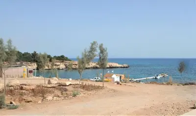 a body of water with a beach and a dock at Kapparis Apartment Mythical Sands in Protaras