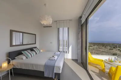 a bedroom with a bed and a large window at Protaras Greco Hilltop Views in Protaras