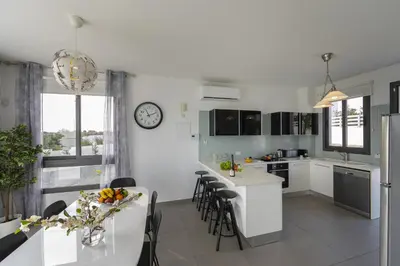 a kitchen with white cabinets and a table with chairs at Protaras Greco Hilltop Views in Protaras