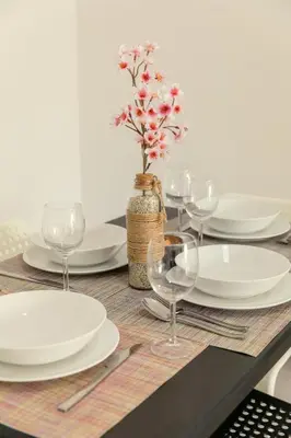 a table with plates and glasses and a vase with flowers at Savvas City Centre Flat in Larnaka