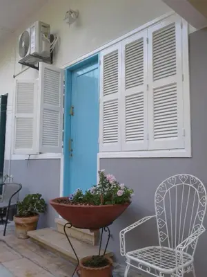 a porch with a chair and a blue door at Sparrows Nest in Larnaka