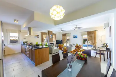 a large kitchen and living room with a table and chairs at Villa Malama in Paralimni