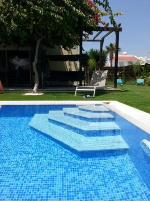 a swimming pool with blue tiles in a yard at Villa Bouboulina Cyprus in Ayia Napa