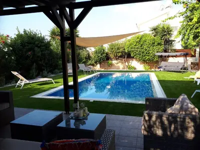 a swimming pool in a yard with a table and chairs at Villa Bouboulina Cyprus in Ayia Napa