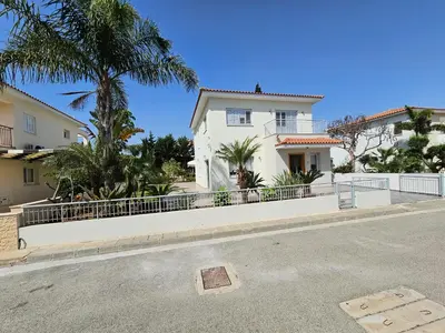 a white house with a fence and palm trees at FAMILY HOME in Protaras