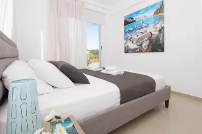 a bedroom with a large bed with a large window at Villa Eden in Ayia Napa