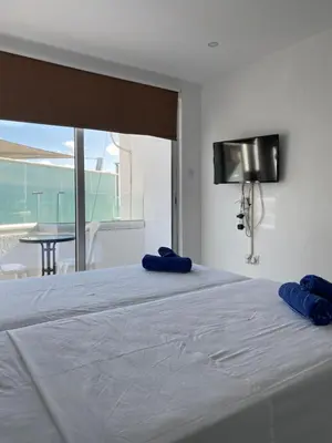 a bed with two blue pillows on top of it at Midtown Napa Apartments in Ayia Napa
