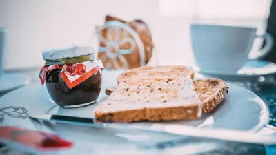 a plate with two slices of bread and a jar of jam at Midtown Napa Apartments in Ayia Napa