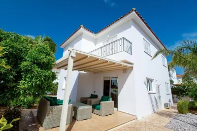 a white house with a balcony and chairs at Villa Nova in Protaras