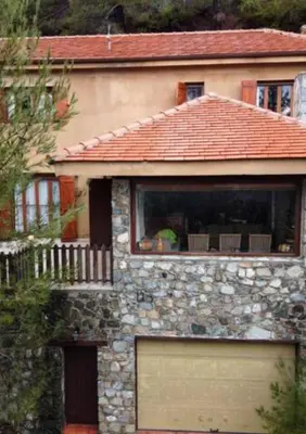 a stone house with a large window and a garage at Kardama HideAway in Kato Amiandos