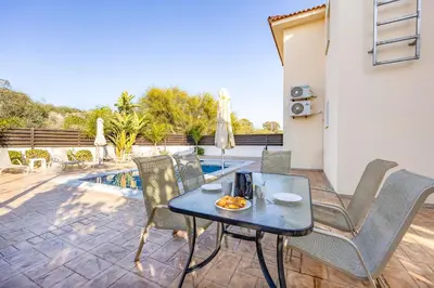 a patio with a table and chairs and a pool at Villa Oceania in Ayia Napa