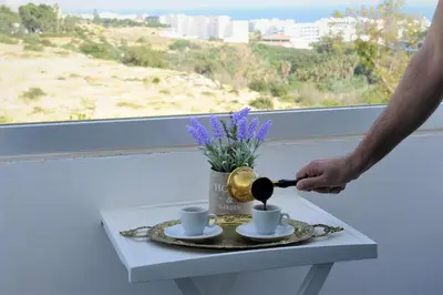a man is pouring coffee into cups on a table at Napa City Apartments in Ayia Napa
