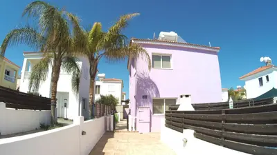 a pink house with palm trees in front of it at Villa Sunrise in Paralimni