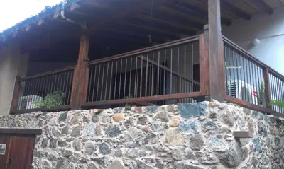 a stone wall in front of a building with a balcony at Patriko Traditional House in Kakopetria