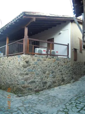 a stone wall in front of a house with a balcony at Patriko Traditional House in Kakopetria