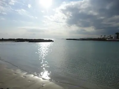 a beach with the sun reflecting on the water at Nissi Sandy Bay C09 in Ayia Napa