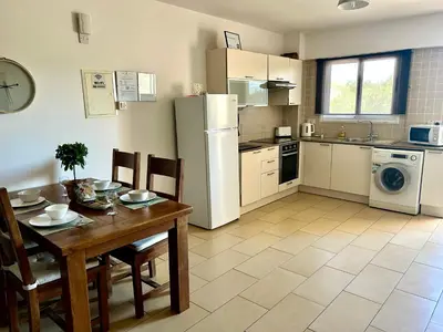 a kitchen with a table and a refrigerator at Nissi Sandy Bay C09 in Ayia Napa