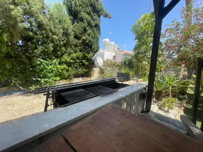 a raised deck with a table in a garden at VILLA CATALEYA Fig Tree Bay Protaras Town Center in Protaras