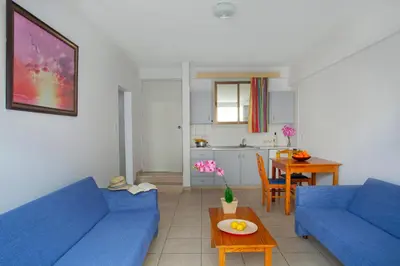 a living room with two blue couches and a table at Paloma Hotel Apartments in Ayia Napa