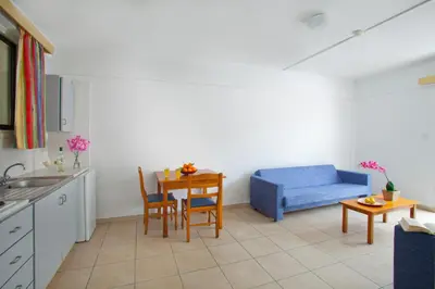 a kitchen with a table and a blue couch at Paloma Hotel Apartments in Ayia Napa