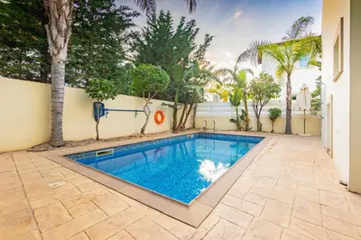 a swimming pool in a yard with trees and a building at Villa Rosita in Paralimni