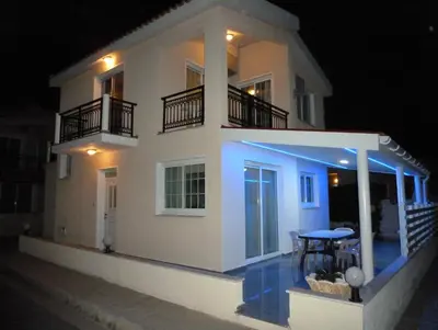 a white house at night with a table in front of it at Philippou Beach Villas & Apartments in Larnaka