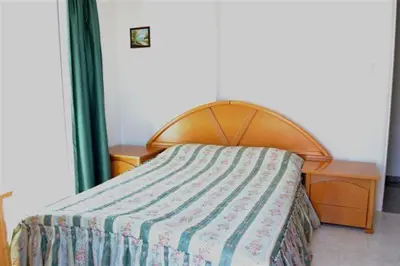 a bedroom with a bed with a wooden head board at Philippou Beach Villas & Apartments in Larnaka