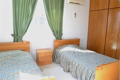 a bedroom with two beds and a window with curtains at Philippou Beach Villas & Apartments in Larnaka