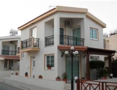 a large white house with balconies on a street at Philippou Beach Villas & Apartments in Larnaka