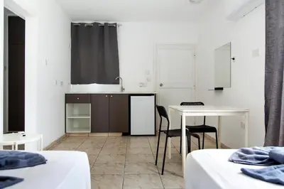 a room with two beds and a table and a kitchen at Summer's Hotel Apartments in Ayia Napa