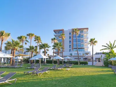 a group of lounge chairs and palm trees in a park at Leonardo Crystal Cove Hotel & Spa – Adults only in Protaras