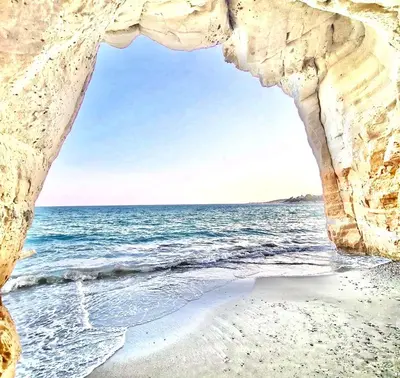 a view of the ocean through a rock cave at Governors Beach Costas Apts in Governors Beach