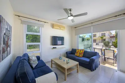 a living room with two blue couches and a tv at Protaras Villa Marilia in Protaras
