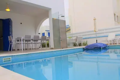 a large swimming pool with chairs and a table at Villa St. Nicolas 8 - Protaras in Protaras