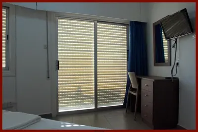 a bedroom with a desk and a window with blinds at St. George Rent Rooms in Larnaka