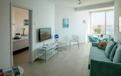 a living room with a blue couch and a television at Front-Row - Skyline Retreat - Pool Access in Larnaka
