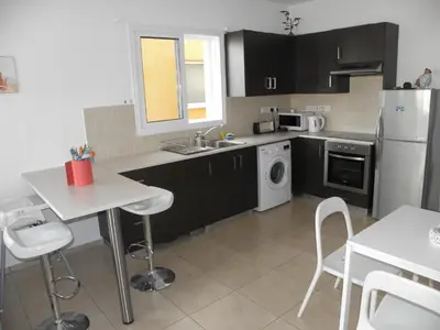 a kitchen with black cabinets and a white refrigerator at Cosy apartment in a luxury resort in Paralimni