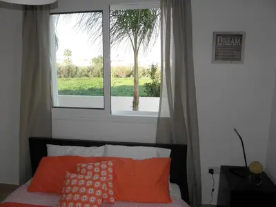 a bed with orange pillows in front of a window at Cosy apartment in a luxury resort in Paralimni