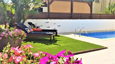 a garden with a bench and a swimming pool at Palm Paradise Villa in Ayia Napa