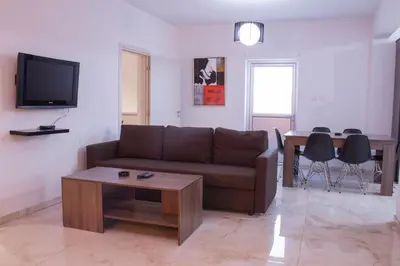 a living room with a brown couch and a table at Makronissos Beach Villas in Ayia Napa