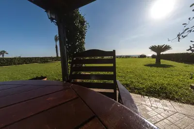 a wooden table and a chair sitting next to a field at Blue Bay Beach House in Larnaka