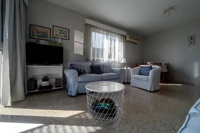 a living room with two couches and a flat screen tv at Blue Bay Beach House in Larnaka