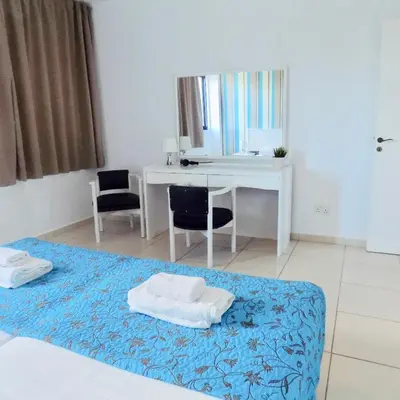a bedroom with a bed and a desk and a mirror at Margarita Napa Apartments in Ayia Napa