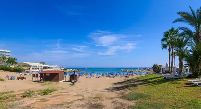 a beach with people sitting on the sand and the ocean at Villa Elaine in Paralimni