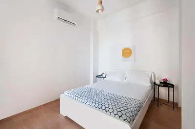 a white bedroom with a bed with blue and white sheets at Welcome! Perfect Location-City Center in Larnaka