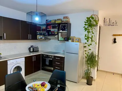 a kitchen with a white refrigerator and a table and chairs at Fat Cow Apartment 103 in Larnaka