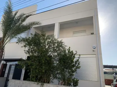 a white house with trees in front of it at Strovolos Value Suites in Strovolos